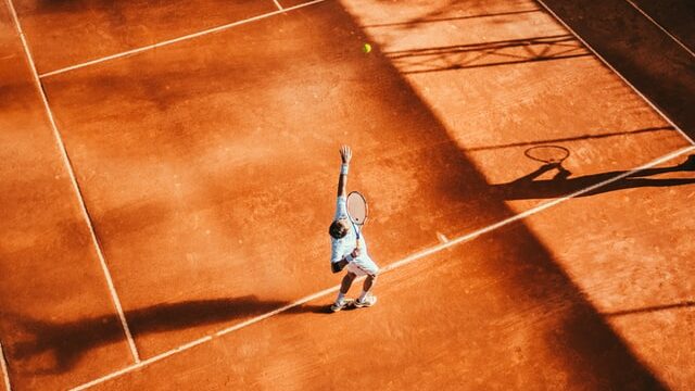 Tennis player making a service on gravel